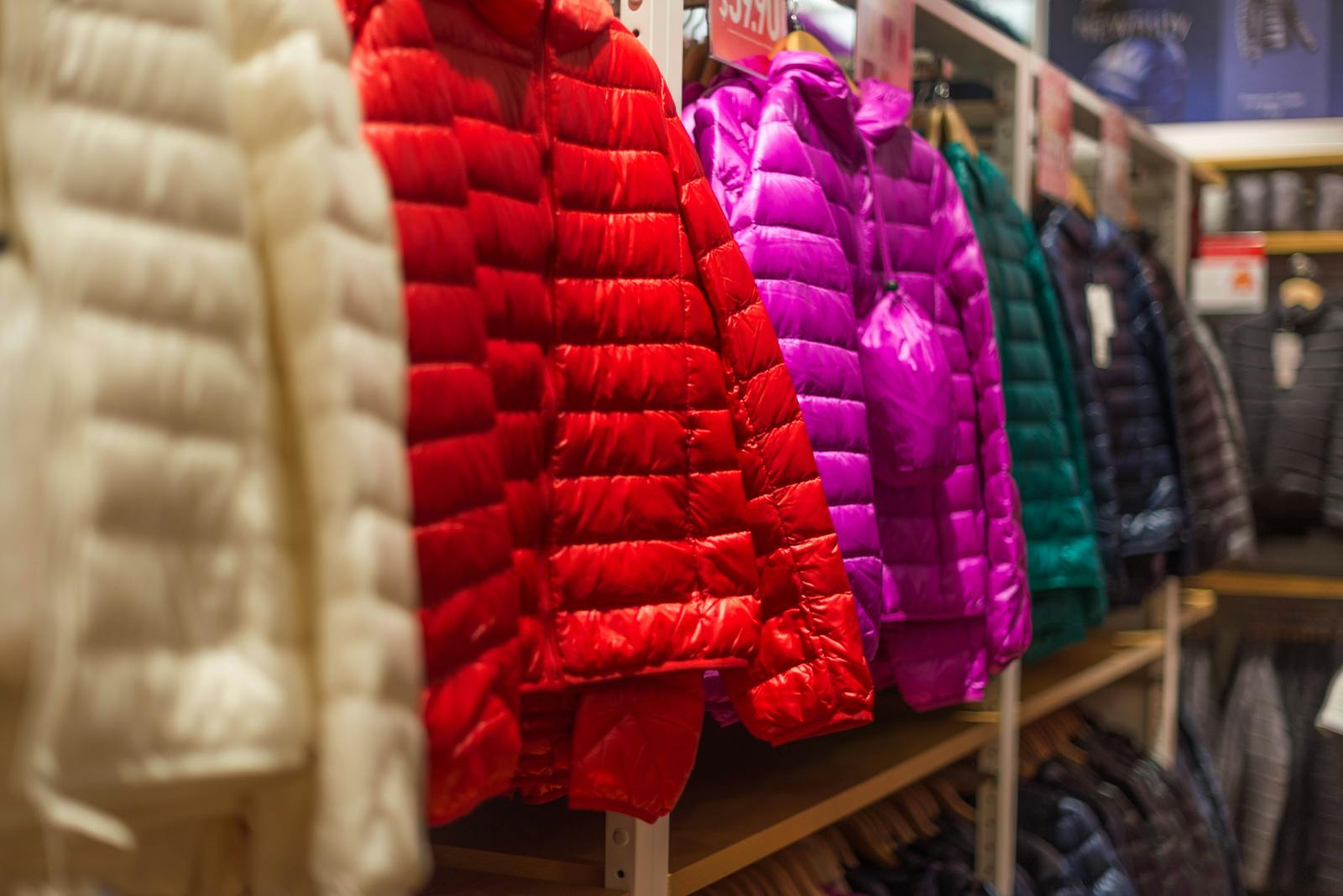 Vibrant winter jackets on display in a clothing store, showcasing a variety of colors for shoppers.